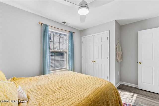 bedroom with wood finished floors, a ceiling fan, visible vents, baseboards, and a closet