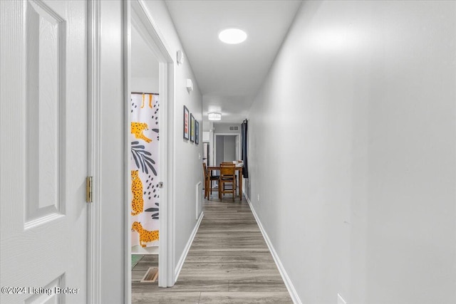 hallway featuring light wood-style flooring and baseboards