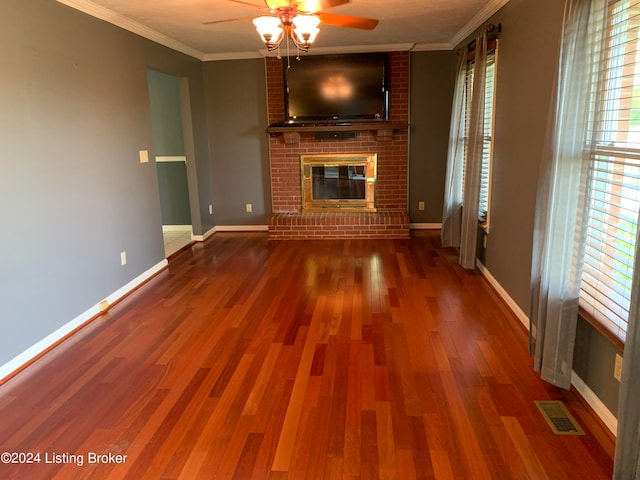 unfurnished living room with hardwood / wood-style floors, ornamental molding, and a brick fireplace