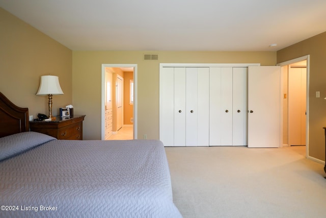 bedroom featuring ensuite bath and light colored carpet