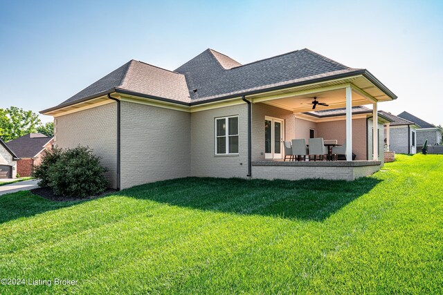 rear view of property featuring ceiling fan and a yard