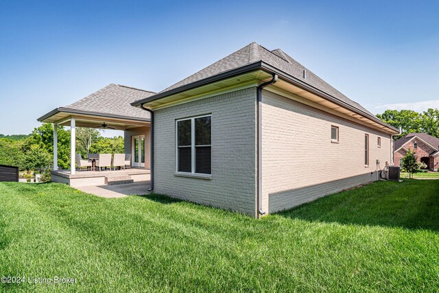 view of side of property featuring a yard, a patio area, and central air condition unit