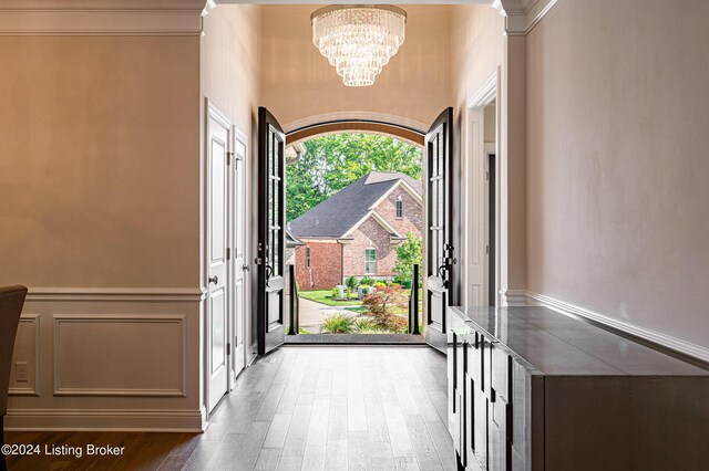 entryway featuring a towering ceiling, hardwood / wood-style floors, and a notable chandelier