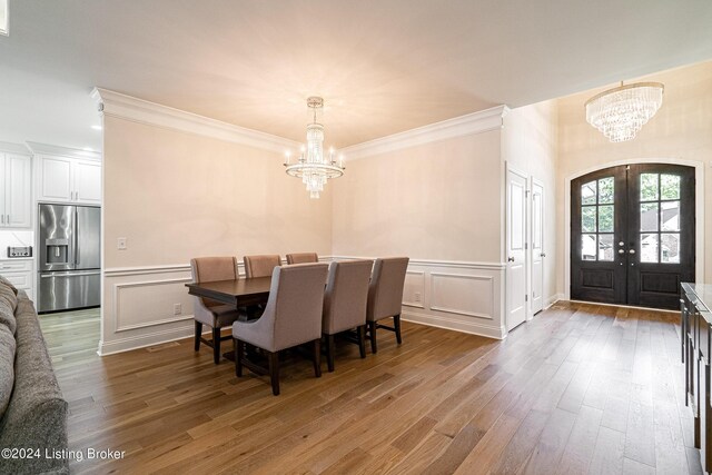 dining room featuring hardwood / wood-style flooring, crown molding, a notable chandelier, and french doors