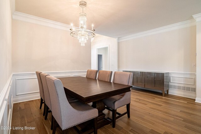 dining space featuring wood-type flooring, an inviting chandelier, and ornamental molding