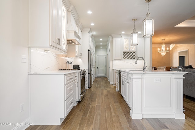 kitchen featuring hanging light fixtures, sink, light wood-type flooring, and decorative backsplash