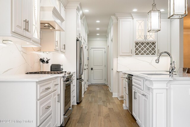 kitchen featuring hanging light fixtures, light hardwood / wood-style floors, premium range hood, decorative backsplash, and ornamental molding