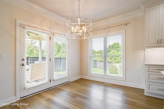 unfurnished dining area featuring hardwood / wood-style flooring, a chandelier, and crown molding