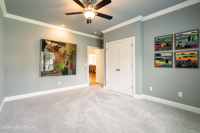 unfurnished bedroom with ornamental molding, a closet, ceiling fan, and carpet flooring