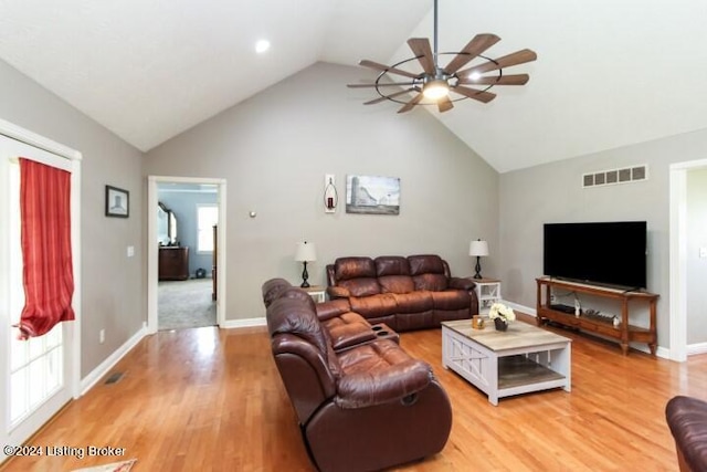 carpeted living room with ceiling fan and high vaulted ceiling