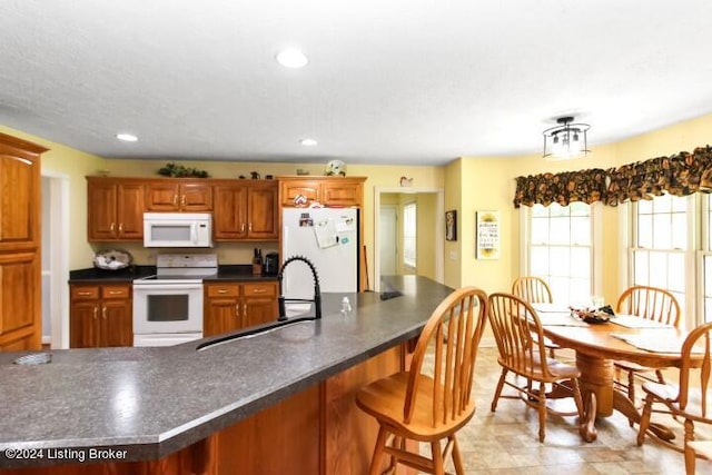 kitchen featuring sink, white appliances, a breakfast bar, and light tile patterned floors