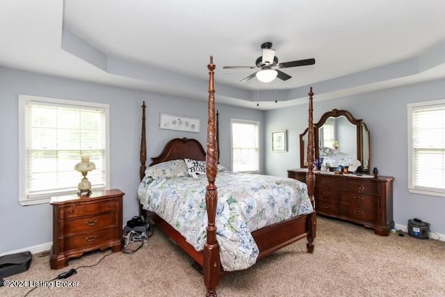 carpeted bedroom featuring ceiling fan and a tray ceiling