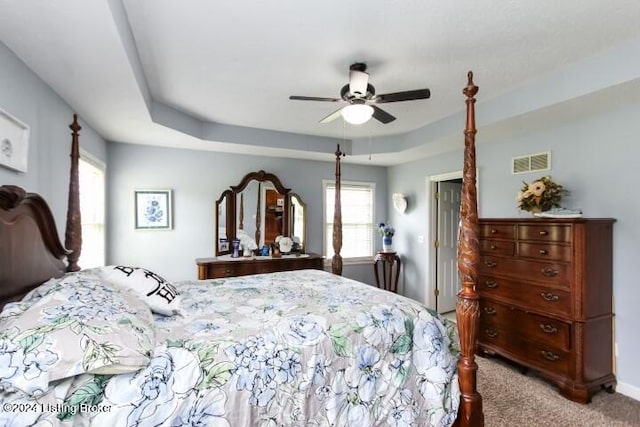 bedroom featuring ceiling fan, carpet floors, and a tray ceiling