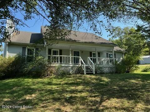 rear view of property featuring a yard and covered porch