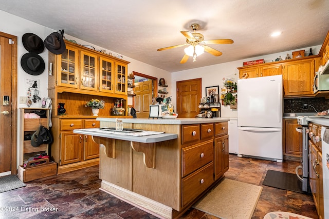 kitchen featuring a textured ceiling, a kitchen island, ceiling fan, a breakfast bar, and appliances with stainless steel finishes