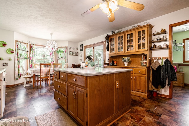 kitchen with ceiling fan with notable chandelier, a center island, a wealth of natural light, and decorative light fixtures