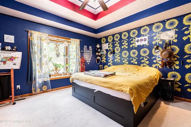 bedroom with carpet flooring, a tray ceiling, and ceiling fan