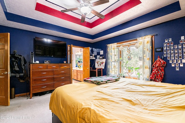 bedroom with light colored carpet, a raised ceiling, a textured ceiling, and ceiling fan