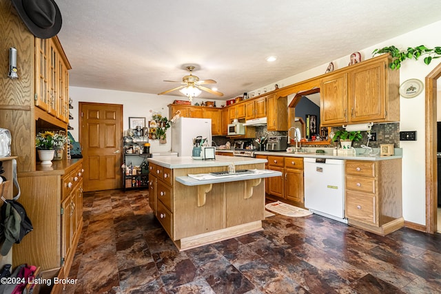 kitchen with white appliances, a kitchen island, ceiling fan, and tasteful backsplash