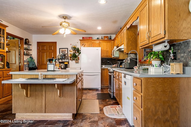 kitchen with a kitchen breakfast bar, white appliances, ceiling fan, and decorative backsplash