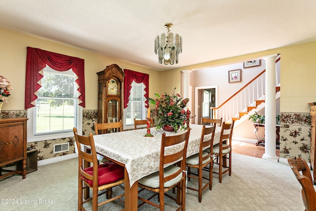 dining room with a textured ceiling, a notable chandelier, ornate columns, and light carpet