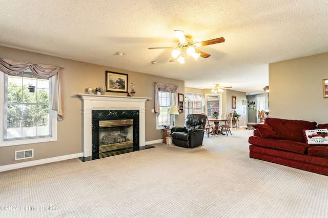 living room with ceiling fan, plenty of natural light, carpet, and a fireplace