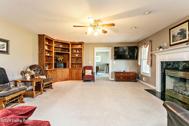 sitting room with ceiling fan, carpet flooring, a textured ceiling, and a fireplace