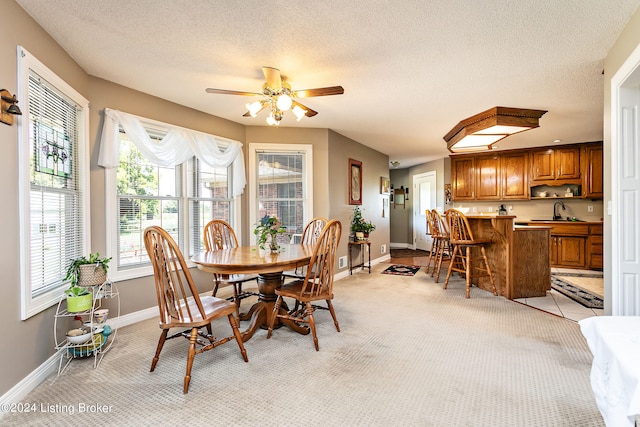 carpeted dining space featuring a textured ceiling, ceiling fan, and sink