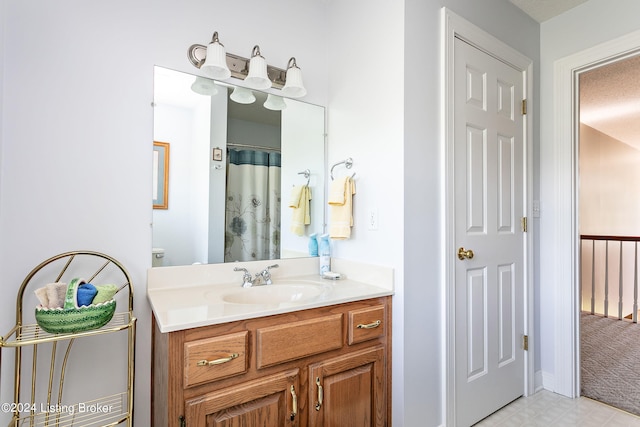 bathroom with a textured ceiling, toilet, tile patterned flooring, and vanity