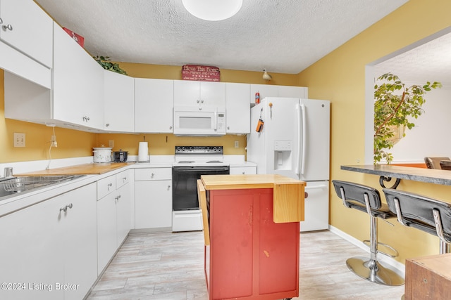 kitchen featuring white cabinetry, light wood-type flooring, and white appliances