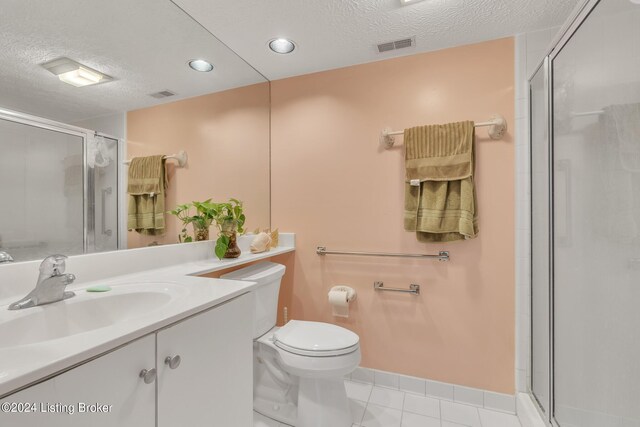 bathroom featuring toilet, tile patterned flooring, vanity, a textured ceiling, and a shower with shower door