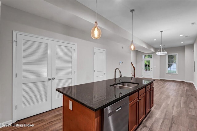 kitchen featuring dark stone countertops, dishwasher, hardwood / wood-style floors, sink, and an island with sink