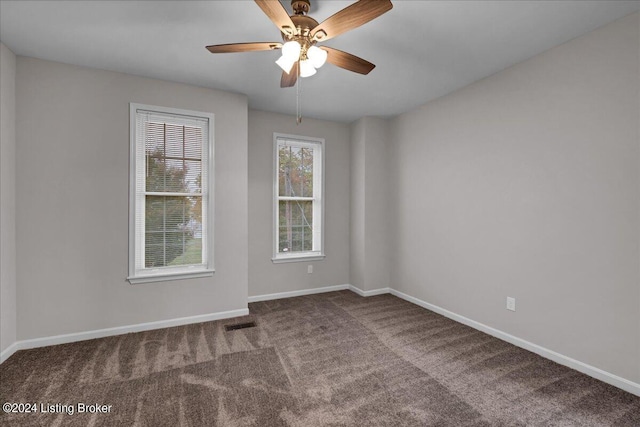 carpeted spare room featuring a healthy amount of sunlight and ceiling fan