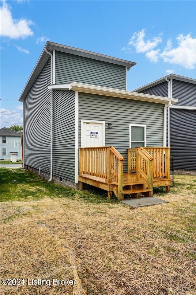 rear view of house with a wooden deck and a yard