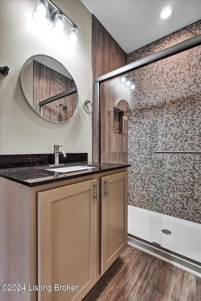 bathroom featuring a shower with shower door, hardwood / wood-style flooring, and vanity