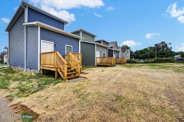 back of property with a wooden deck and a lawn