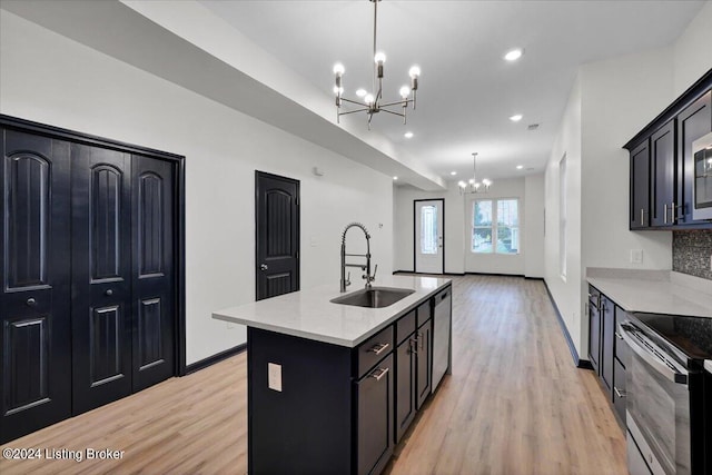 kitchen with sink, light stone countertops, light wood-type flooring, and a kitchen island with sink