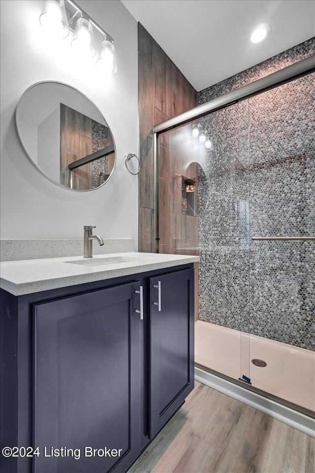 bathroom featuring hardwood / wood-style flooring, a shower with door, and vanity