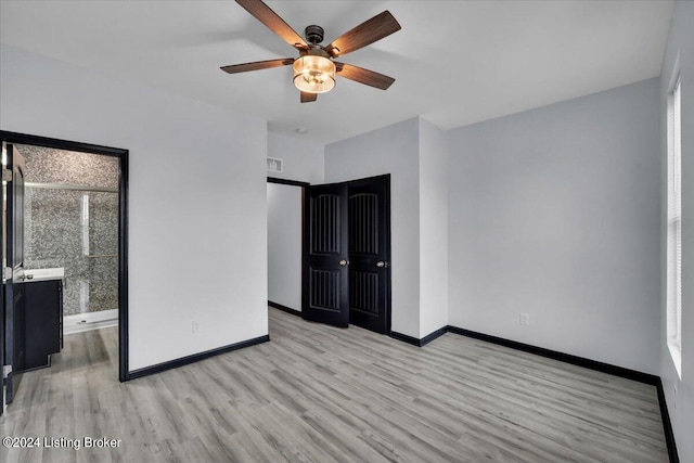 interior space featuring light wood-type flooring, multiple windows, ceiling fan, and a closet