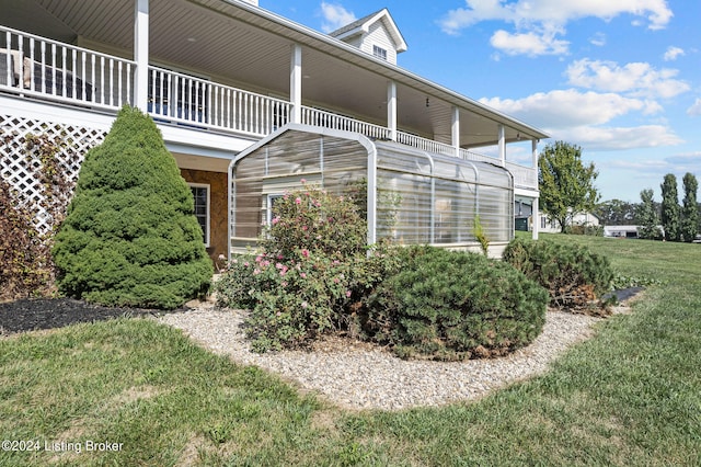 view of property exterior featuring a balcony and a lawn