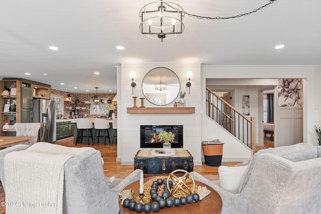 living room with a chandelier, hardwood / wood-style floors, sink, and a large fireplace