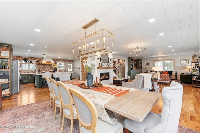 dining area featuring brick wall and light hardwood / wood-style floors