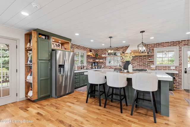 kitchen with stainless steel fridge with ice dispenser, light hardwood / wood-style flooring, green cabinets, and a kitchen island