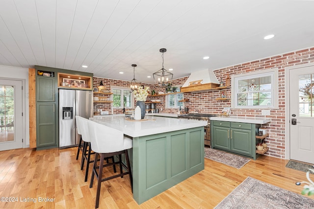 kitchen with a kitchen island, custom exhaust hood, appliances with stainless steel finishes, and green cabinets