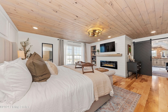 bedroom featuring wood ceiling, light hardwood / wood-style flooring, and a barn door