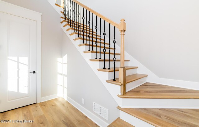 staircase with wood finished floors, visible vents, and baseboards