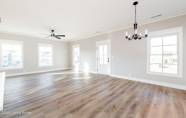 unfurnished living room featuring a healthy amount of sunlight, ornamental molding, ceiling fan with notable chandelier, and hardwood / wood-style flooring