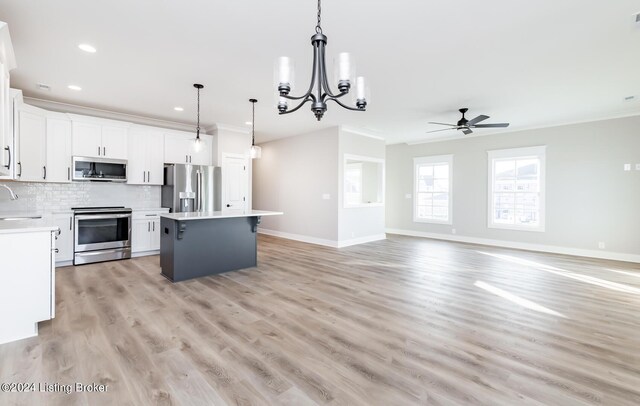 kitchen with tasteful backsplash, appliances with stainless steel finishes, a center island, and crown molding