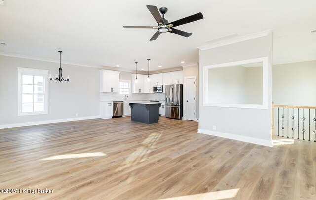unfurnished living room with baseboards, recessed lighting, light wood-style floors, crown molding, and ceiling fan with notable chandelier