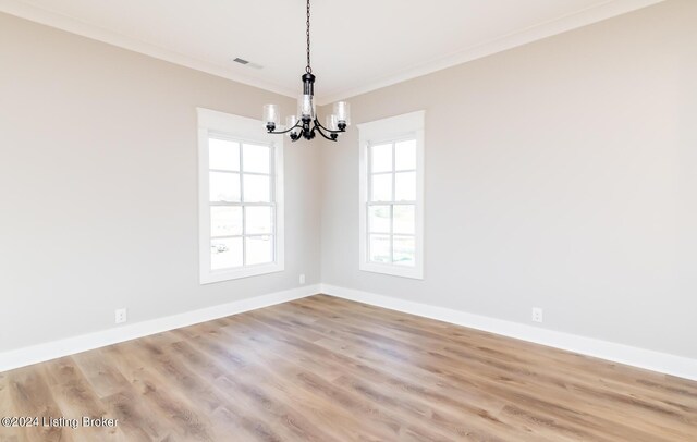 spare room featuring wood finished floors, baseboards, visible vents, crown molding, and a notable chandelier